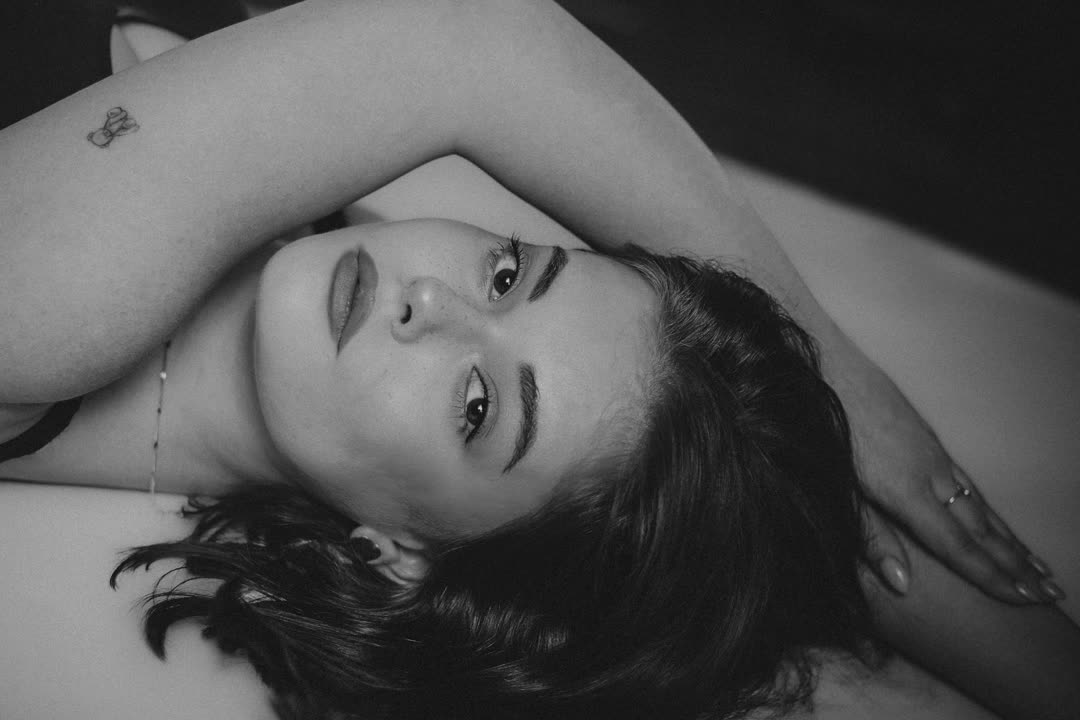 Black-and-white portrait of a woman lying back, arm over her head